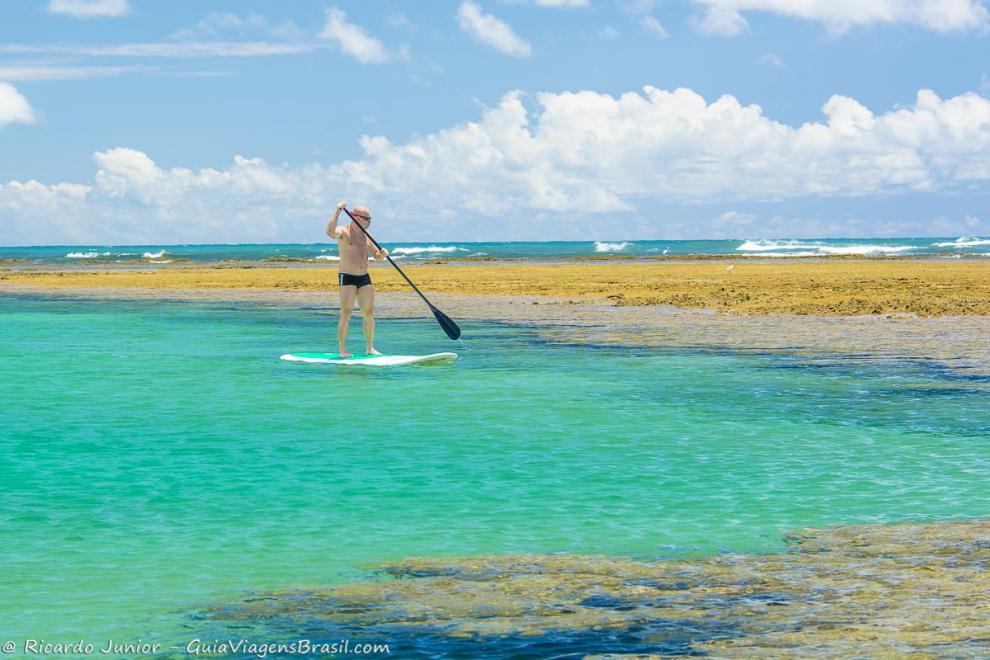 Imagem de um homem praticando stand up paddle na Praia de Taipu de Fora.